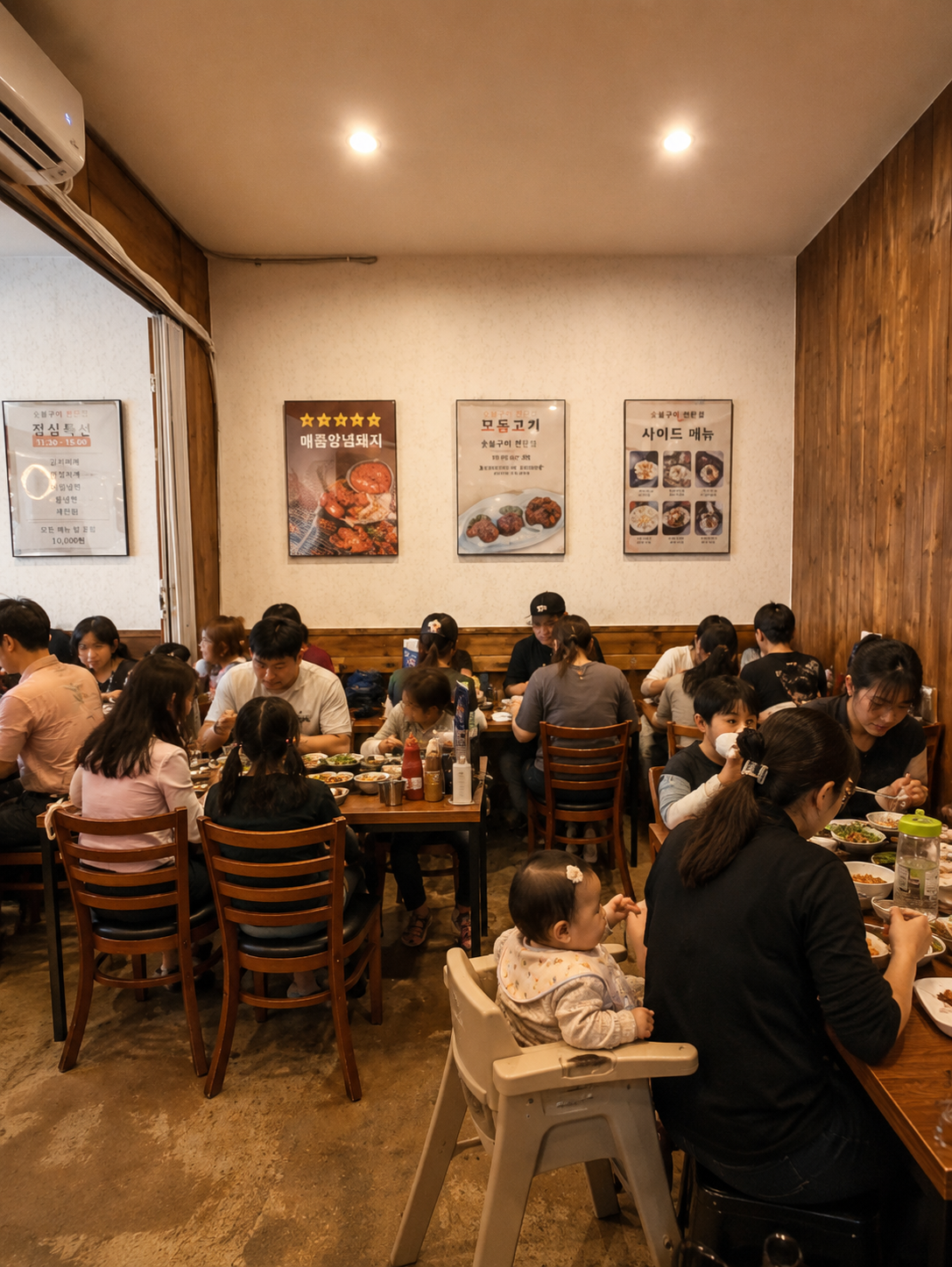 벽면 메뉴 포스터 아래 가족 단위 손님들이 식사 중인 오소불백 룸 내부